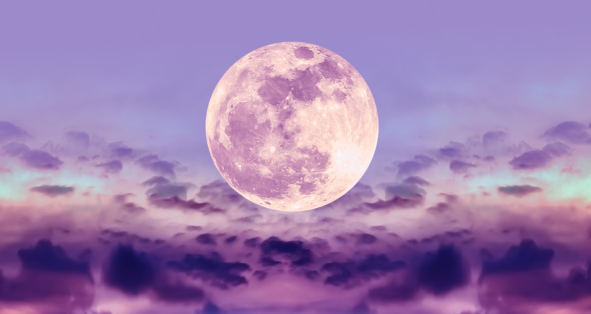 Full Moon colored in pink hovering over clouds.
