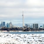 Cityscape of Toronto behind a lake during the winter.