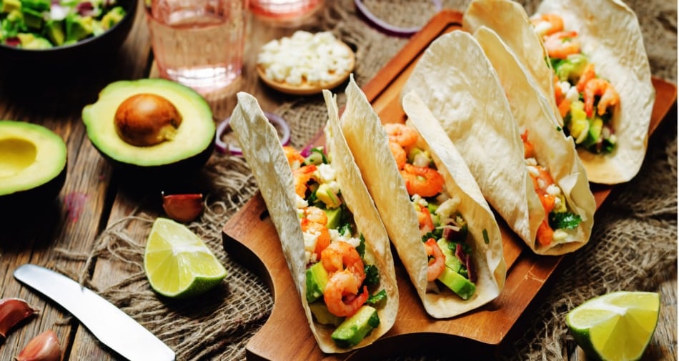 Avocado shrimp tacos with sliced avocados on the side.