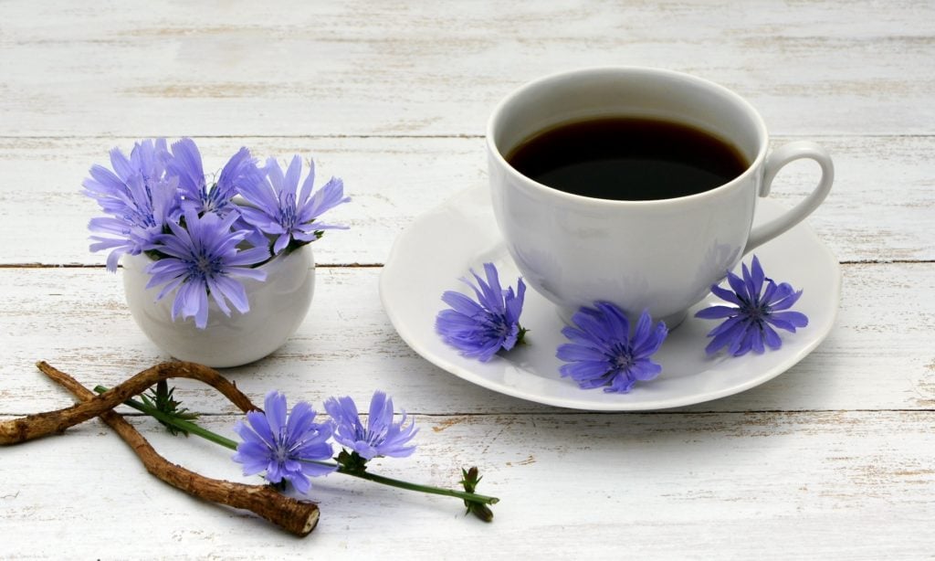 coffee cup with black coffee and purple flowers on plate