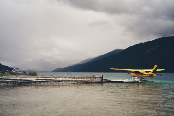 yellow planed docked at a pier with mountains and fog in Alaska