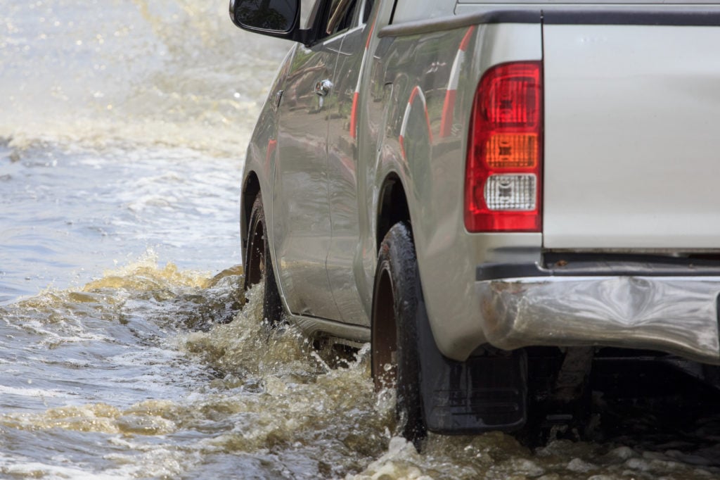 Car splashes through a large puddle on a flooded street