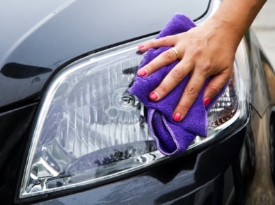 Hand with a purple wipe polishing a headlight.