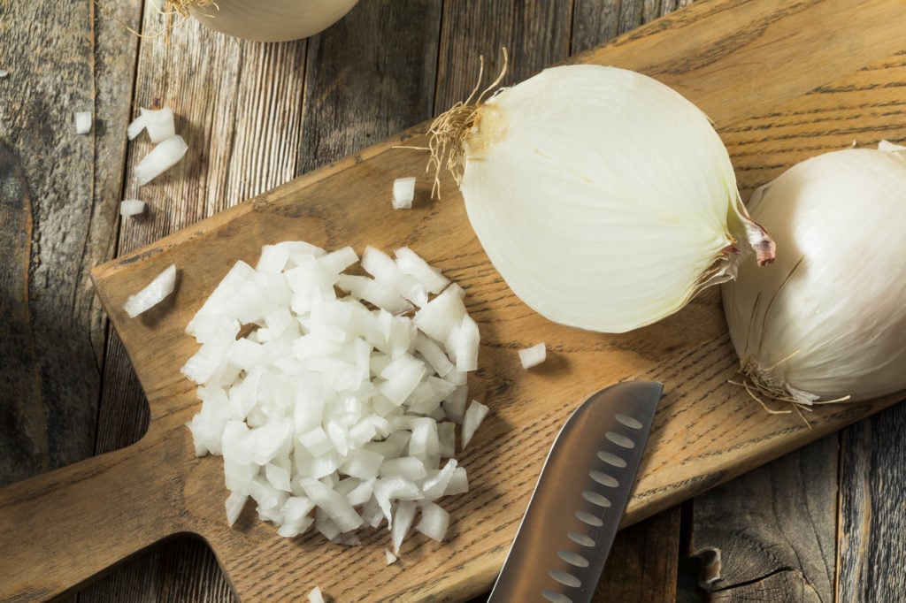 diced onions on a board with other white onions sliced in half