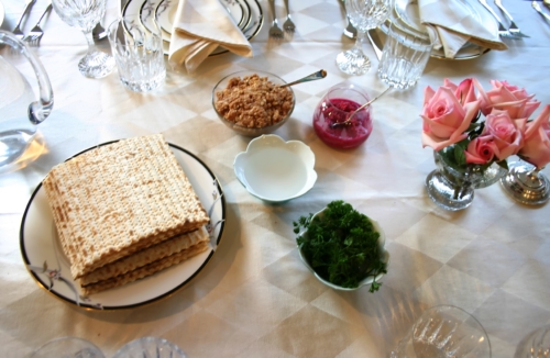 Traditional Passover Seder service table setting with pink flowers.
