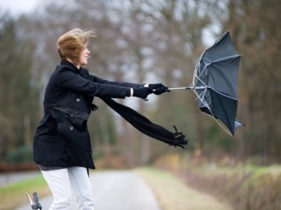 A young woman is fighting against the storm with her umbrella.