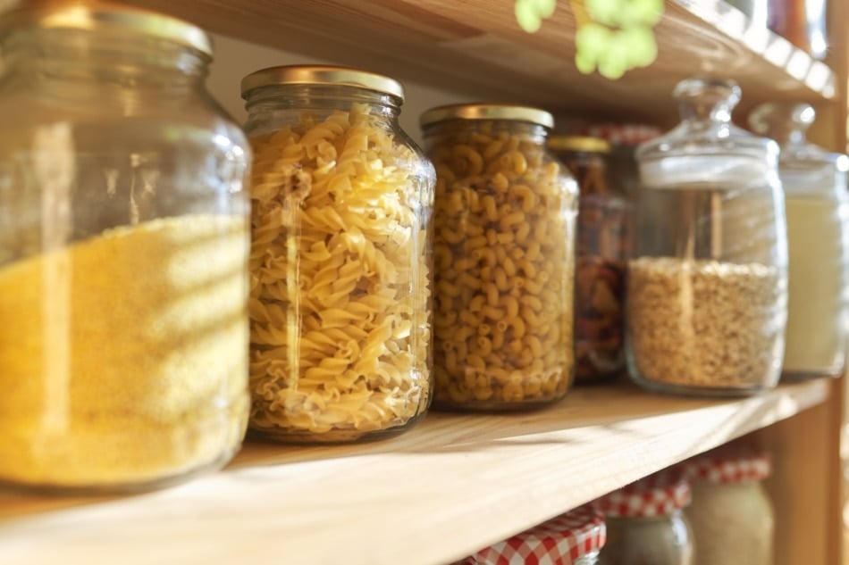 Wooden shelves in pantry for food storage, grain products in storage jars.