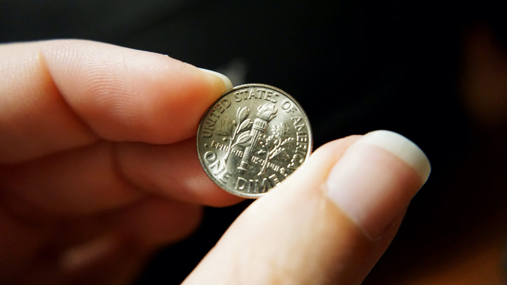 female hand holding up tail end of a dime