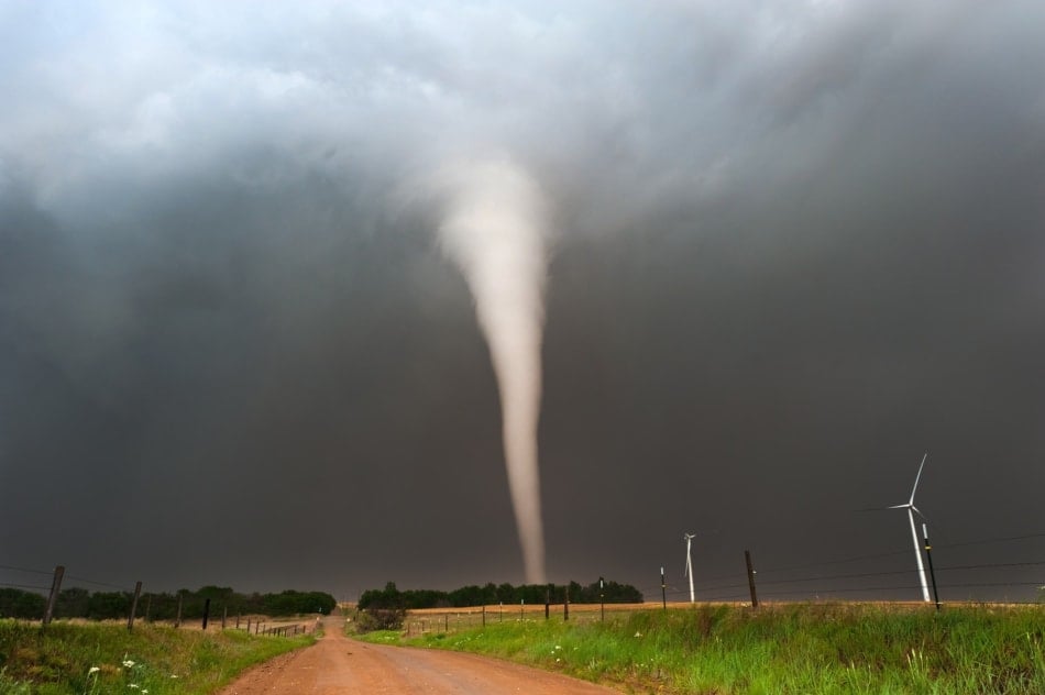 Strong white tornado touching down on a dirt road in Kansas.