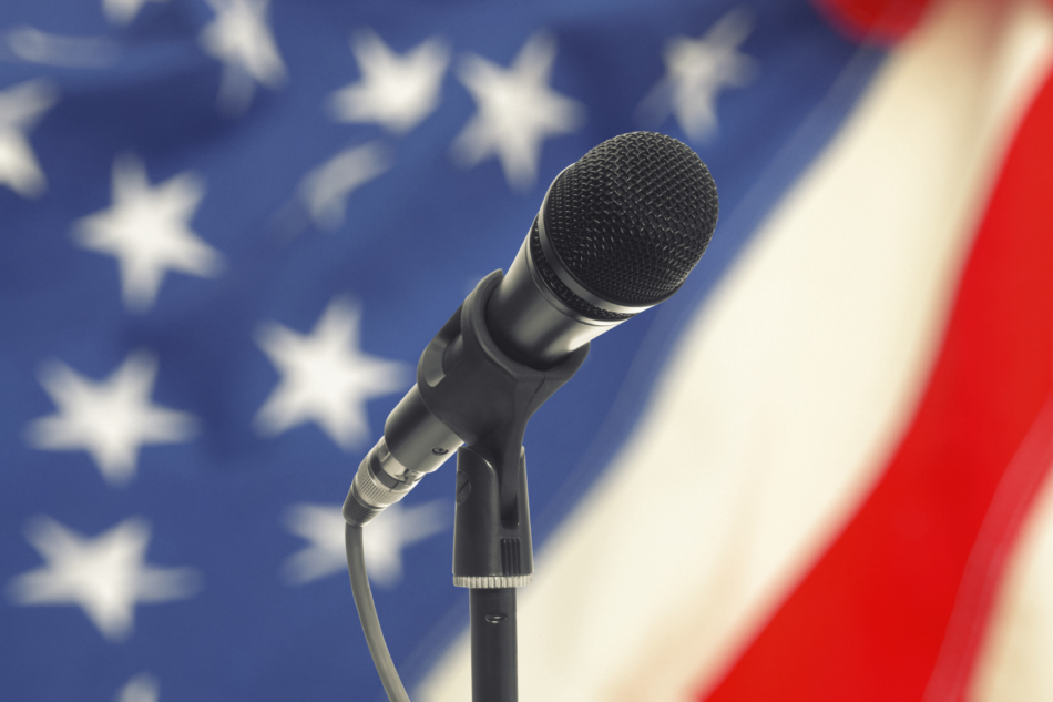 Microphone on stand with US flag on background.