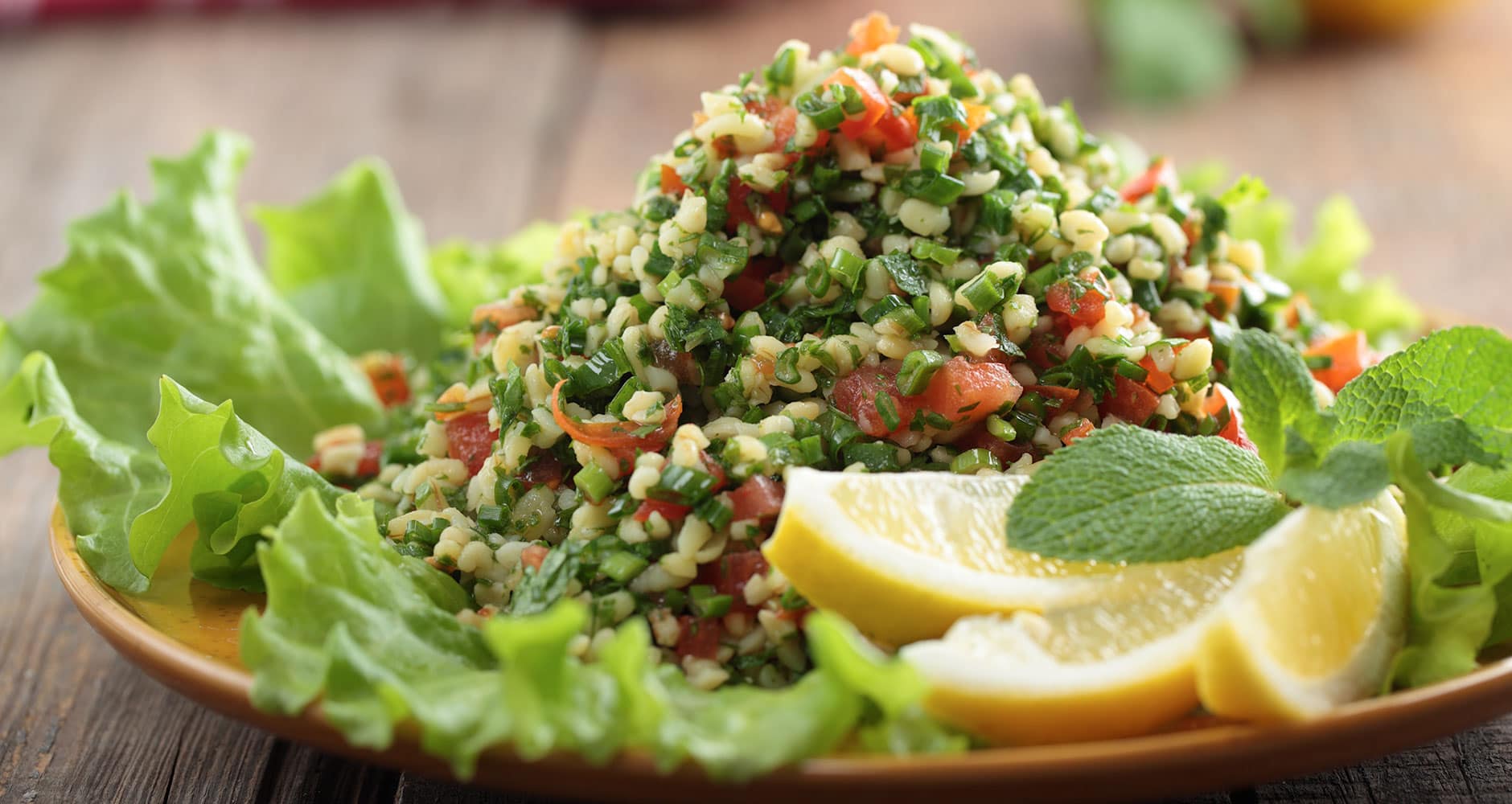 Fresh tabouleh salad on a plate with lemon and mint.