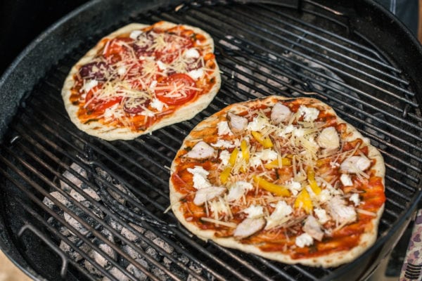 two pizzas on a charcoal grill