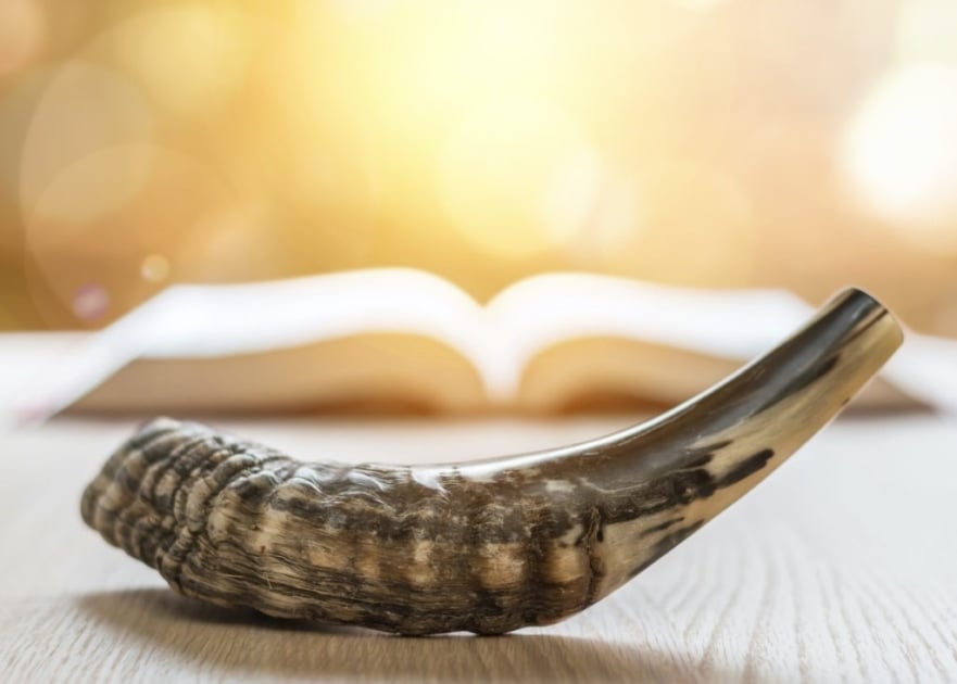 Ram shofar (horn) with religious holy prayer book on table.