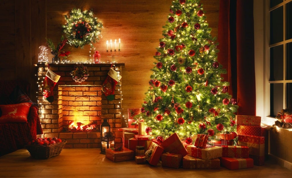 Home decorated for Christmas with the magic glowing tree, fireplace, gifts in dark at night