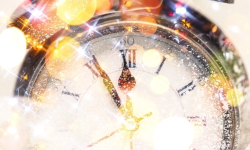 Antique clock about to ring in the new year with party bubbles and confetti.