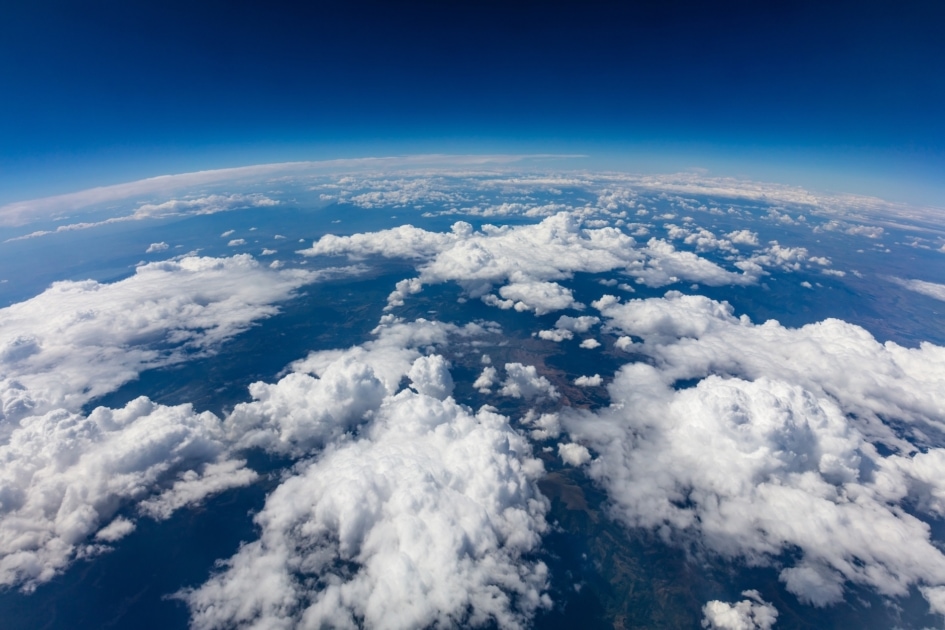 Aerial shot of curvature of planet Earth with blue sky and clouds.