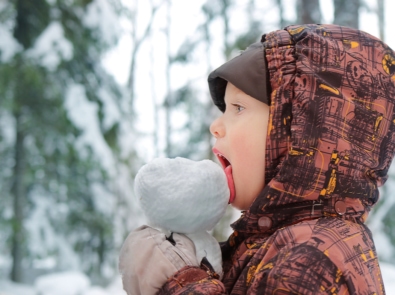 Little happy baby eating snow.