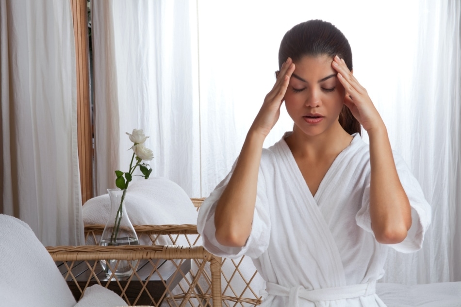 Young woman massaging her face wearing bathrobe.