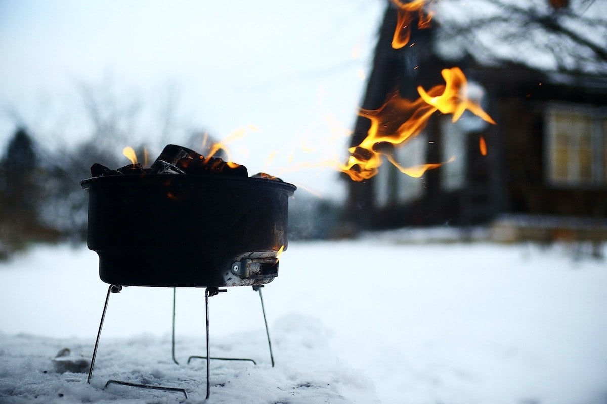 A charcoal grill running outdoors during a winter power outage as a backup cooking option.