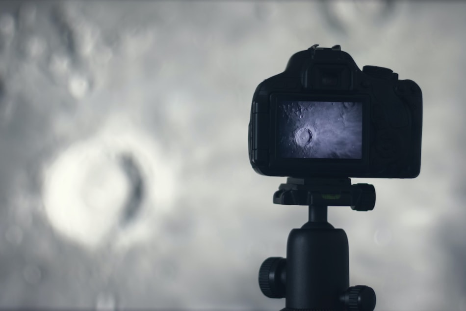 Moon photography. Camera with tripod capturing moon. Moon crater Copernicus Montes Carpatus