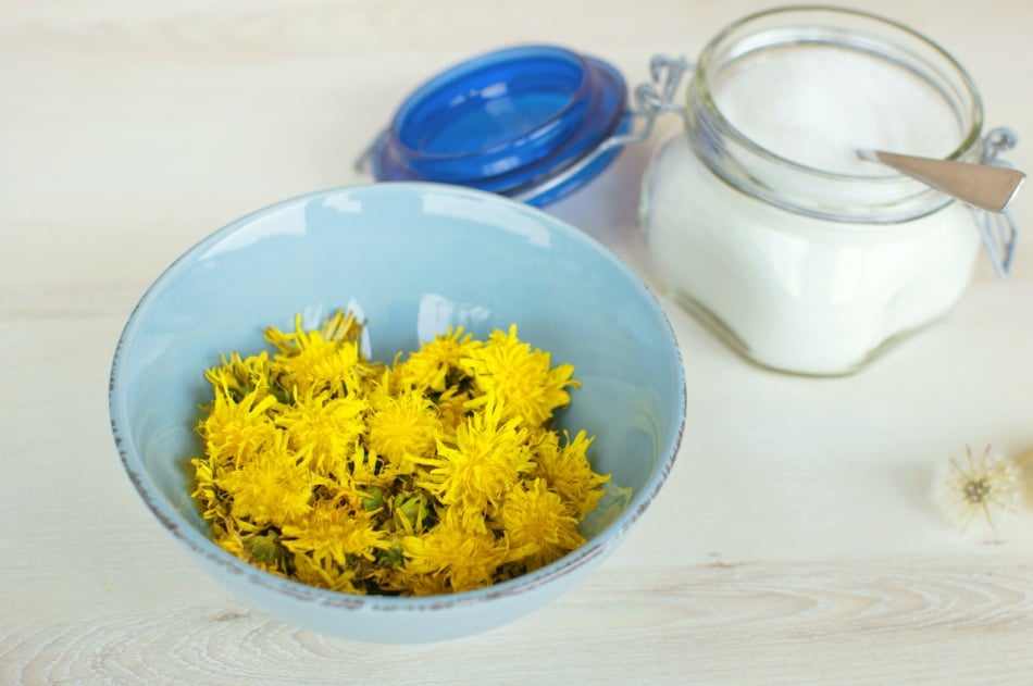 Dandelion flowers in a bowl on wooden table