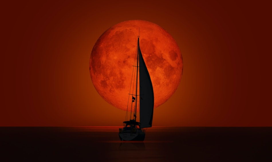 Sailboat against a blood moon lunar eclipse.