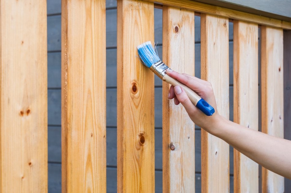 Hand painting slats of a wooden deck