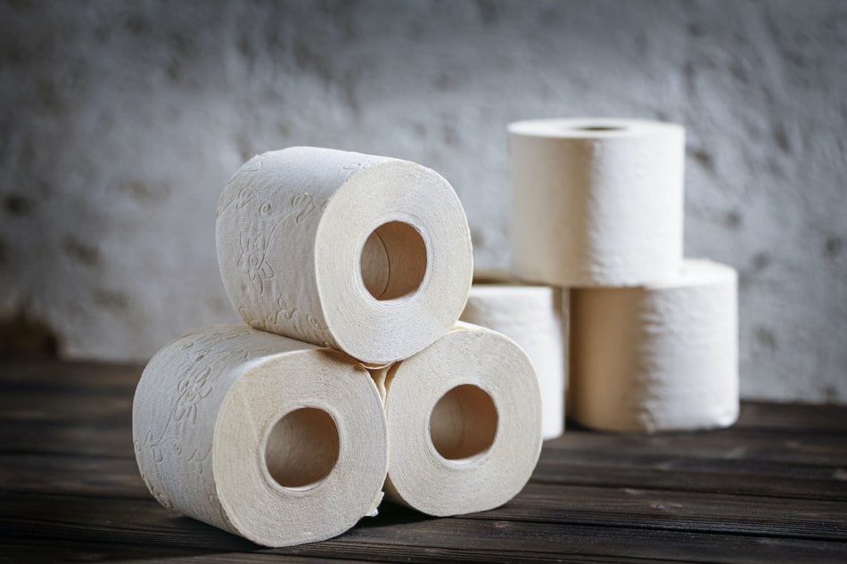 Close-up a few rolls of  toilet paper on a dark wooden table. Grey background. Copy space for text.