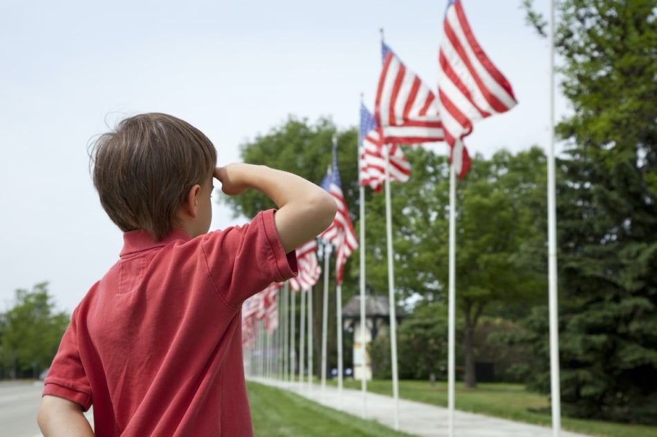 A young boy salutes the flags of a Memorial Day display along a small town street.