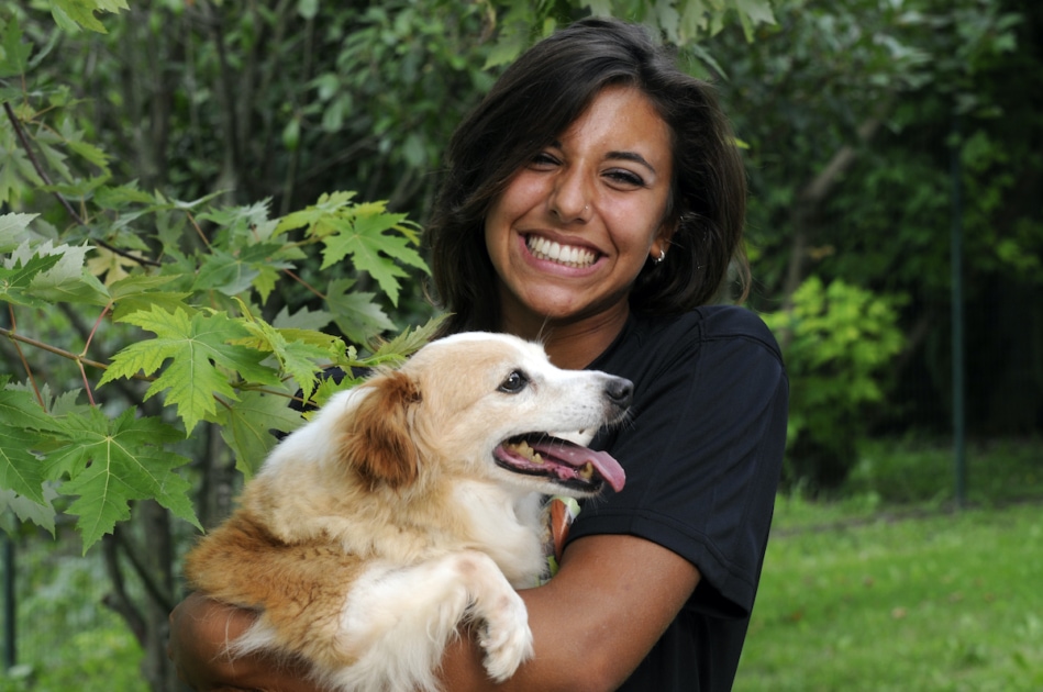 happy woman holding pet dog in garden