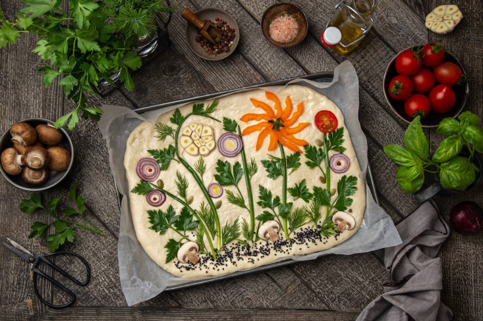 raw floral painting focaccia, garden flatbread art, food trend. Old wooden background, top view