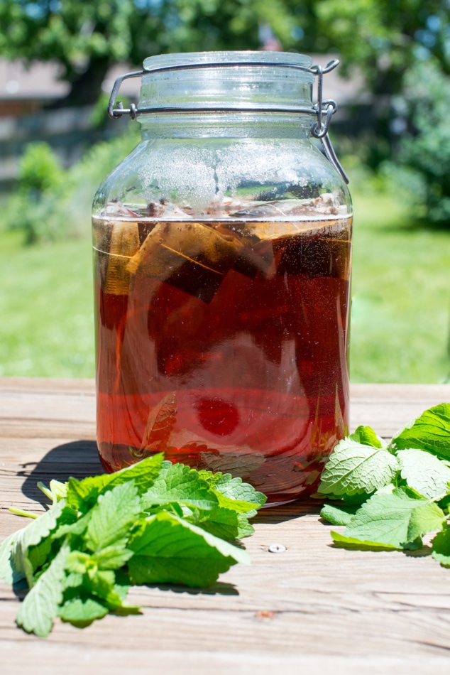 Mason jar of Sun Tea brewing with mint leaves on a table.