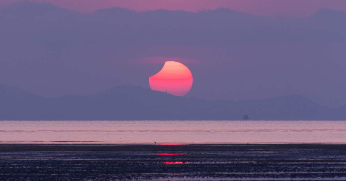 sunrise solar eclipse over the ocean