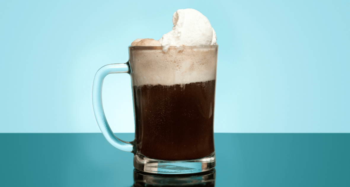 Root beer float in a mug on blue background.