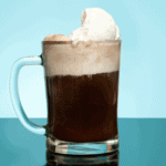 Root beer float in a mug on blue background.