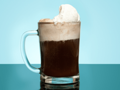 Root beer float in a mug on blue background.