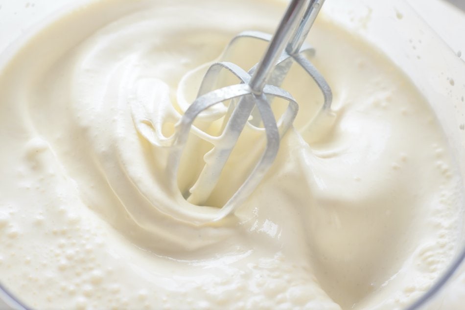 Whipped cream in a bowl with two electric beaters.