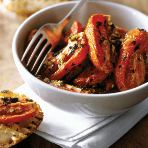 Grilled tomatoes in a bowl with garlic toast