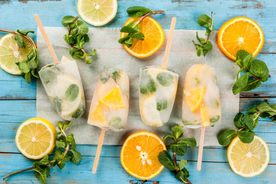 Frozen mojito mocktail ice pops with mint sprigs and lemon slices.