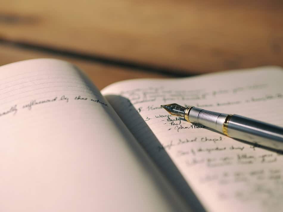 Open journal with pen on wooden surface for planning or writing.