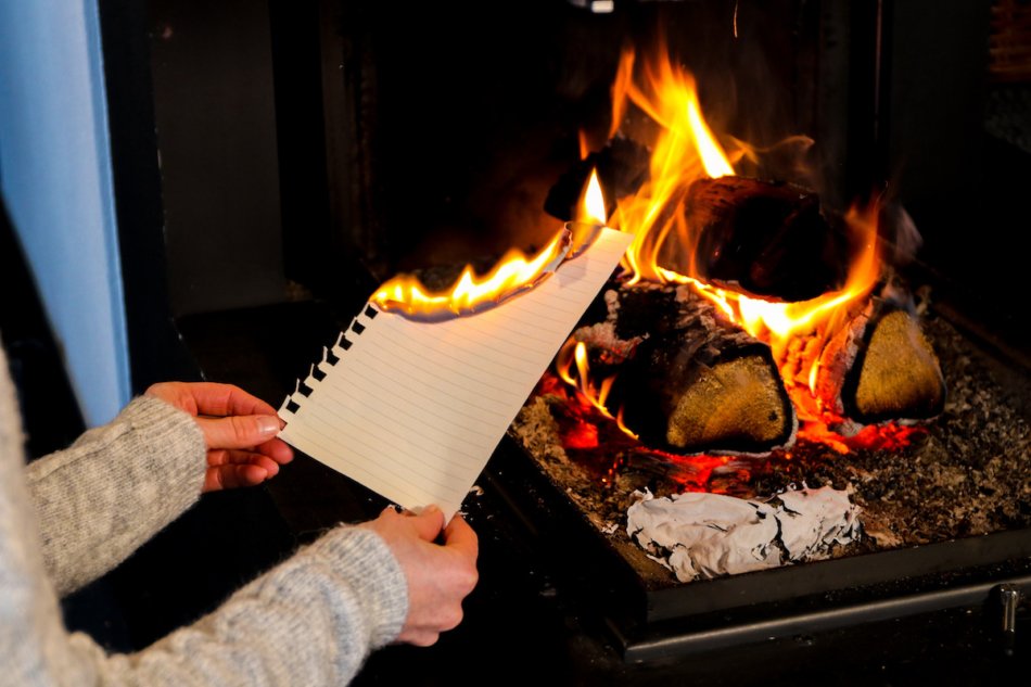 woman burning letter in fireplace.