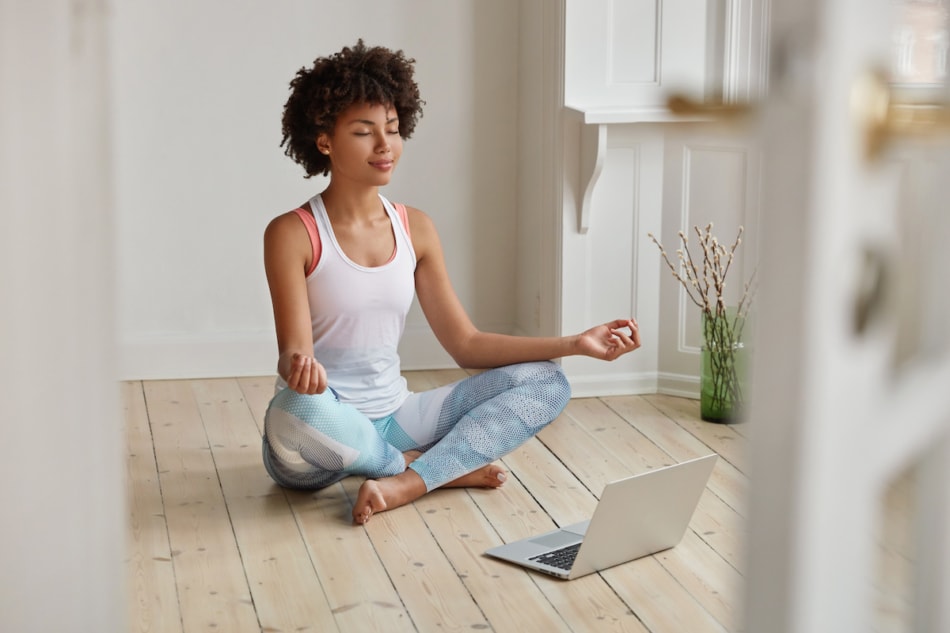 Young woman meditating with laptop