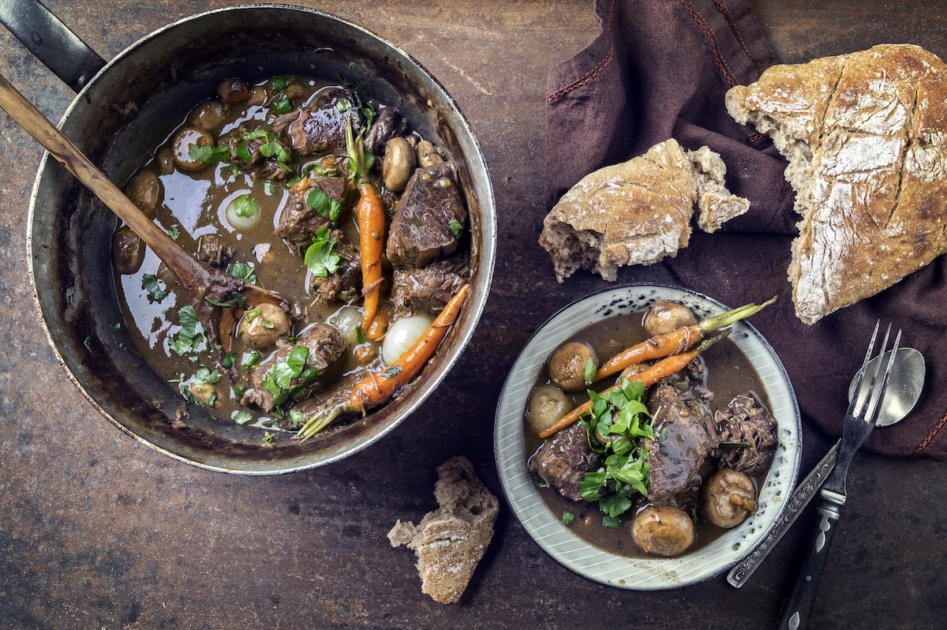 Traditional French bourguignon with vegetable farmhouse bread offered as top view in a design bowl
