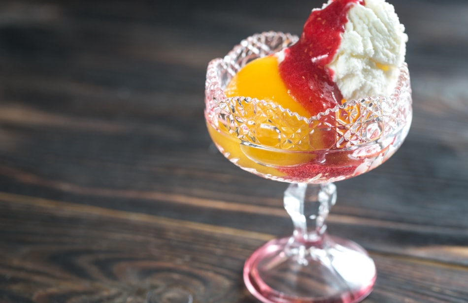 Bowl of Peach Melba - vanilla ice cream with peaches and raspberry sauce.
