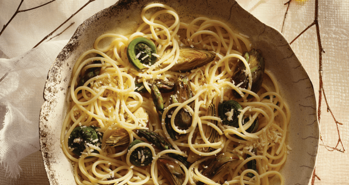 spaghetti with fiddleheads and artichokes in a bowl.
