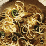 spaghetti with fiddleheads and artichokes in a bowl.