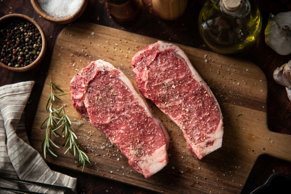 seasoned raw sirloin beef steak on cutting board.