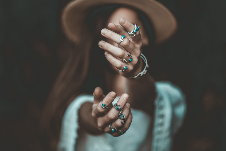 Boho chic woman in a straw hat in a white short blouse and with silver turquoise jewelry. Boho fashion. Hippie style, stylish girl with silver rings