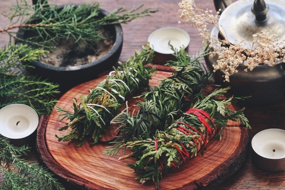 Evergreen cleansing sticks for Yule winter solstice Christmas celebration. Different types of smoke cleanings bundles made from cedar. Alternatives to sage smudge sticks on dark wooden table.