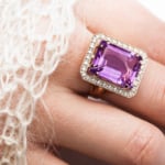 Beautiful golden ring with a large amethyst on a female hand, close-up.